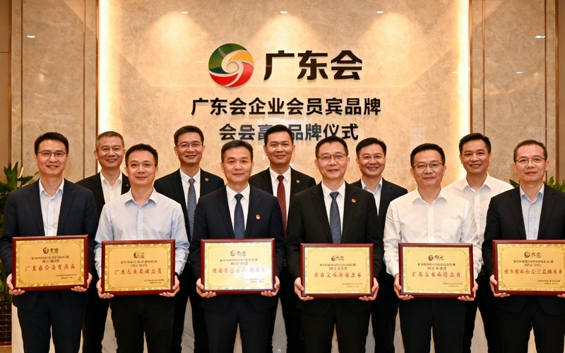广东会企业会员授牌仪式，多位企业代表与广东会高管合影，背景是广东会贵宾厅集团的品牌墙。